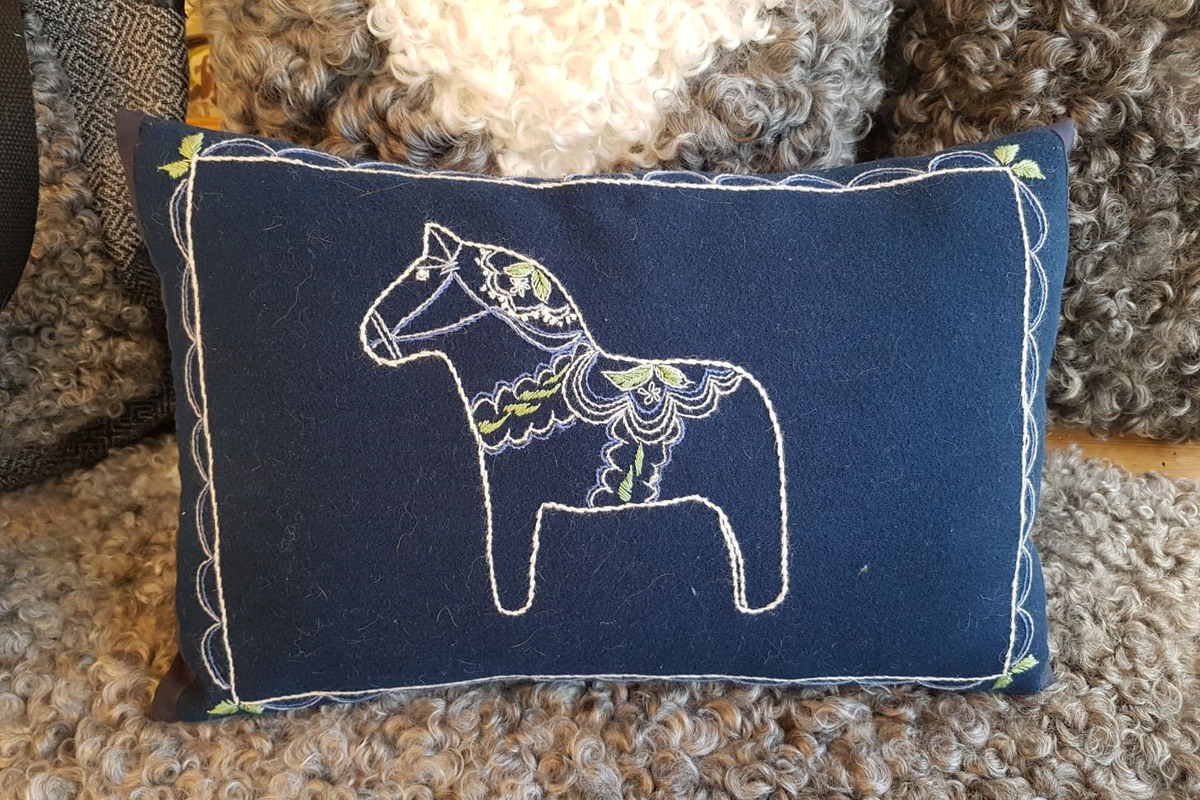 En broderad dalahäst på en kudde.