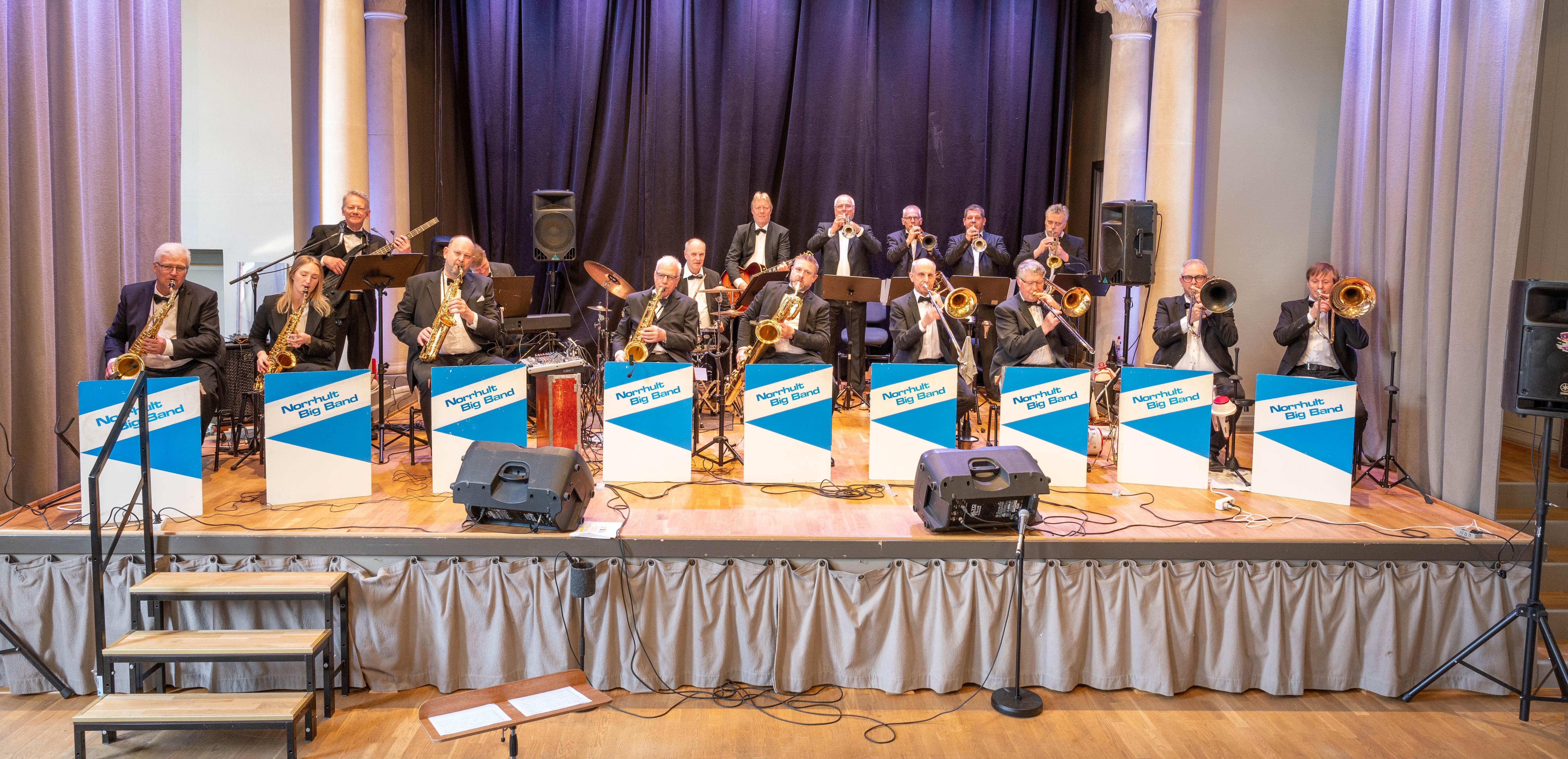 Norrhult Big band sitter på en scen och spelar