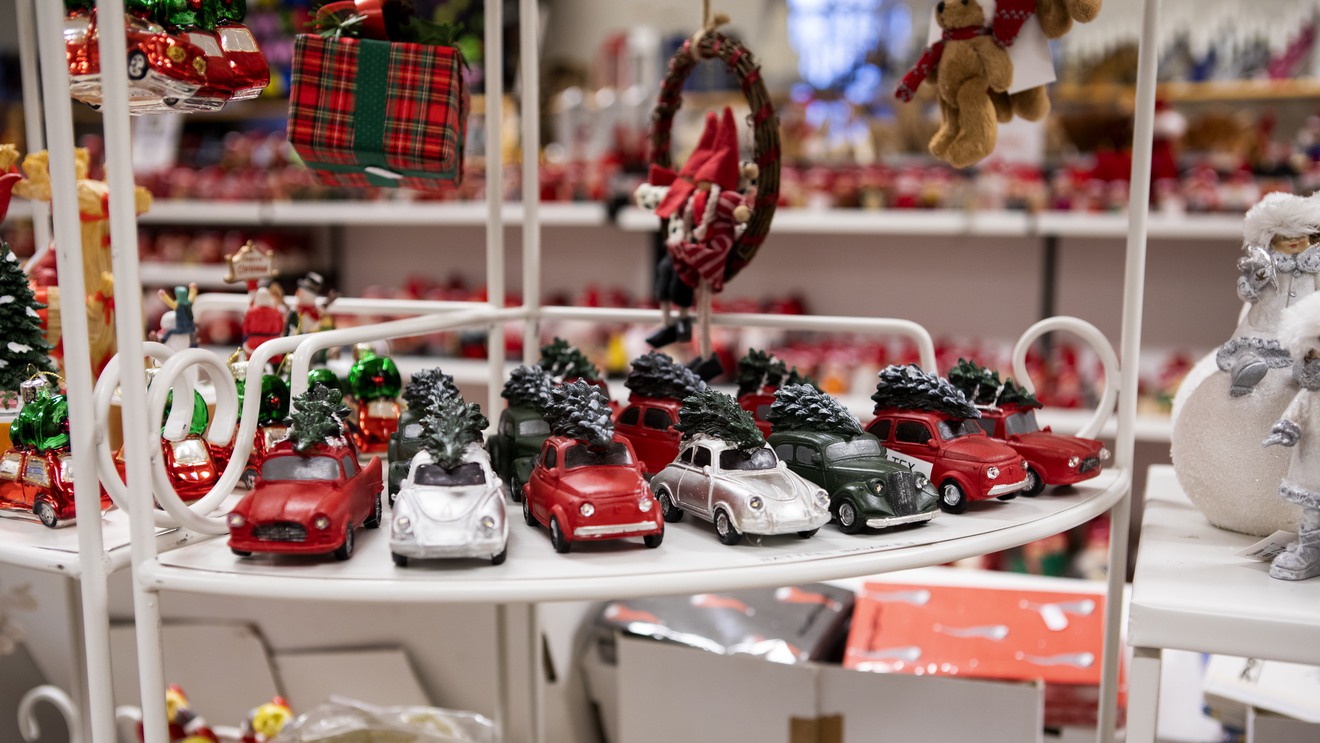 En samling modellbilar med julgranar på taken står på en hylla i en butik där allting har jultema.