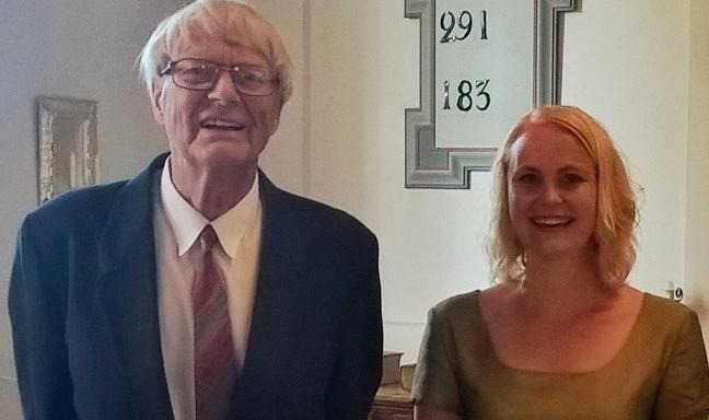 En äldre man och en yngre kvinna ler mot kameran.