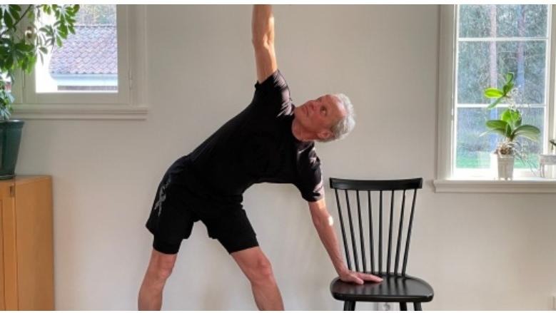en man som utövar yoga vid en stol