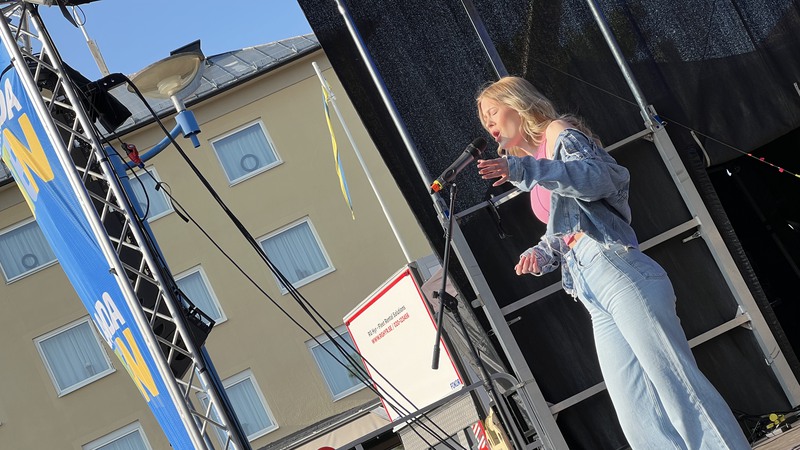 Ung kvinna på scen sjunger i mikrofon