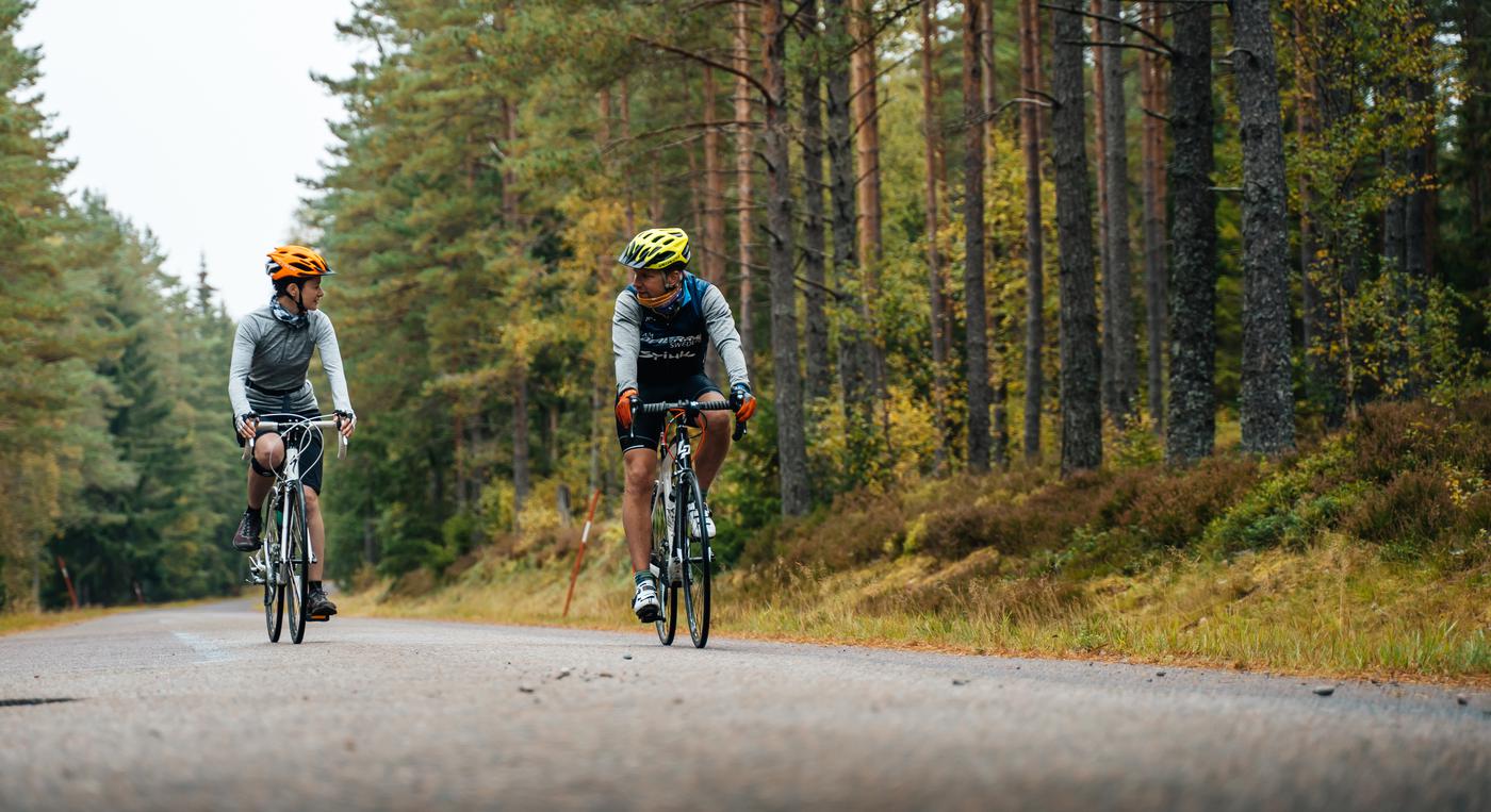 Två cyklister cyklar på en landsväg
