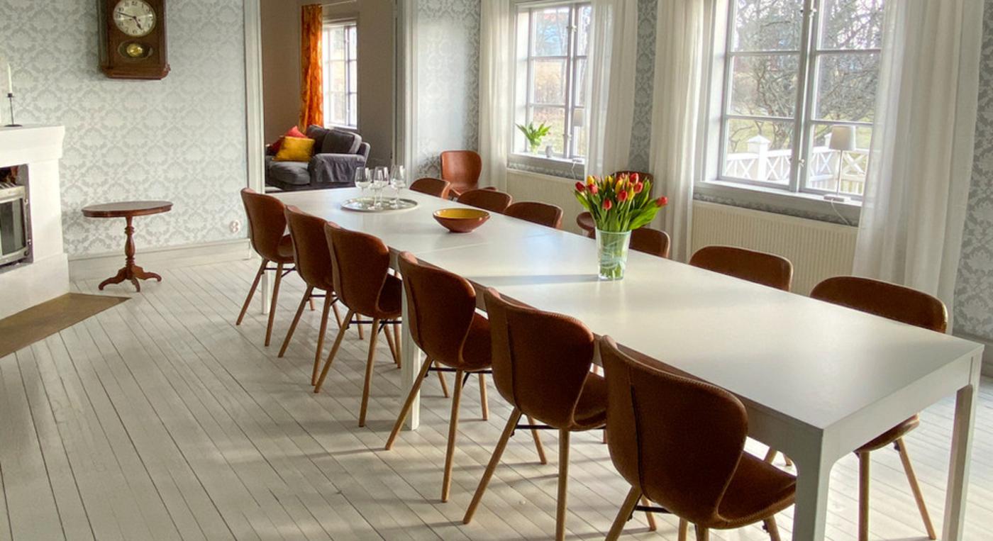 Ett långbord med tolv stolar står i ett stort matsalsrum.