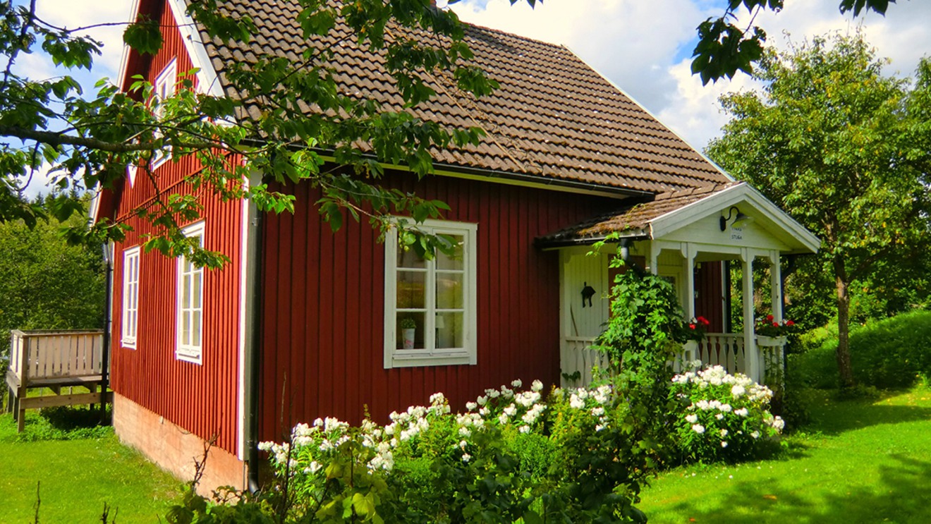 Ett rött hus med en blomstrande trädgård.