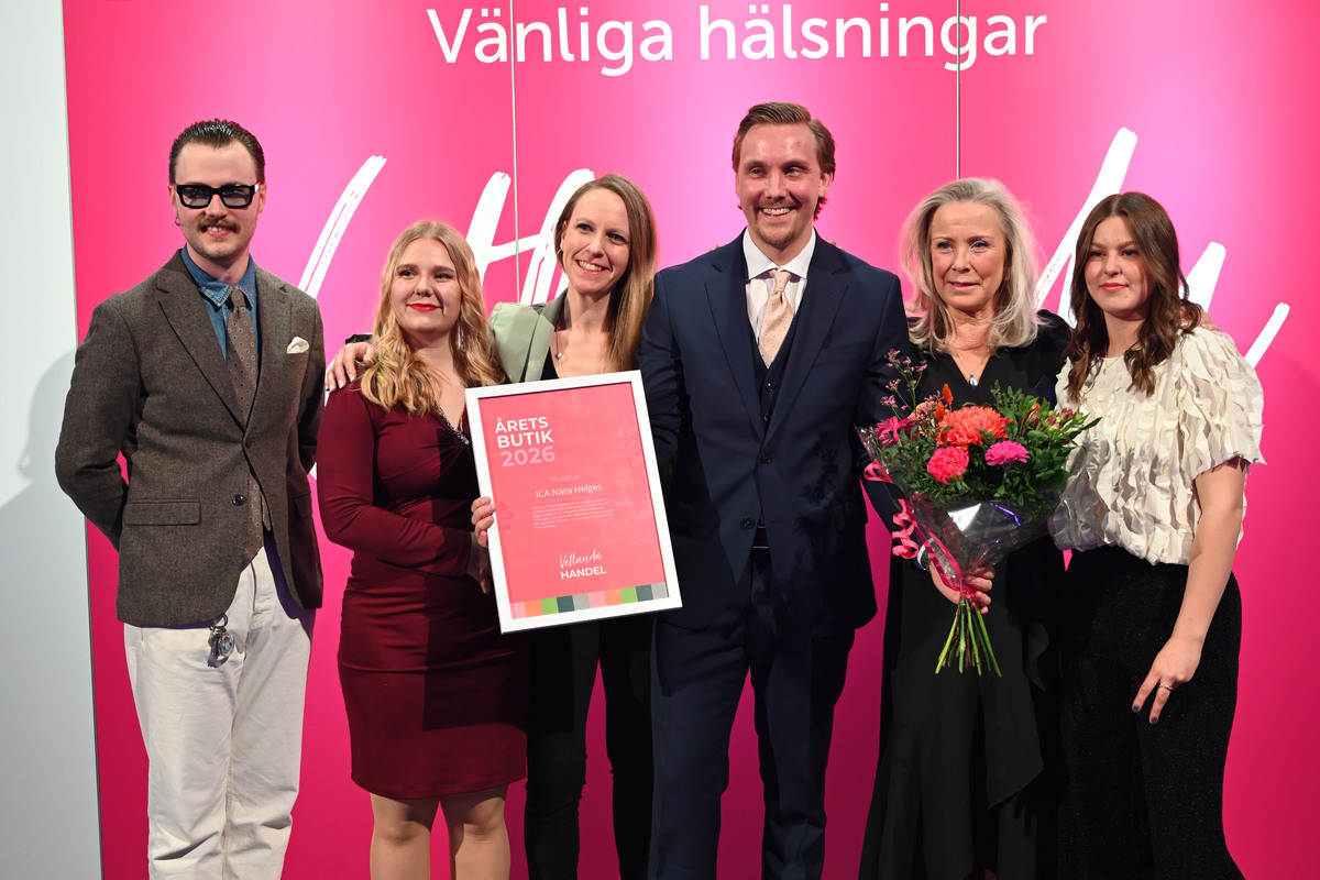 Sex personer står uppställda vid en fotovägg och ler. Tillsammans håller de i ett diplom och en blombukett.