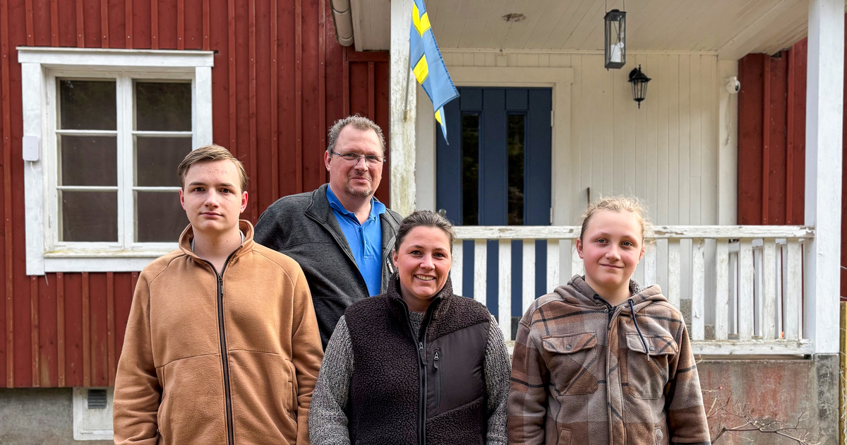 Familjen, två söner, mamma och pappa, uppställda framför det röda huset.