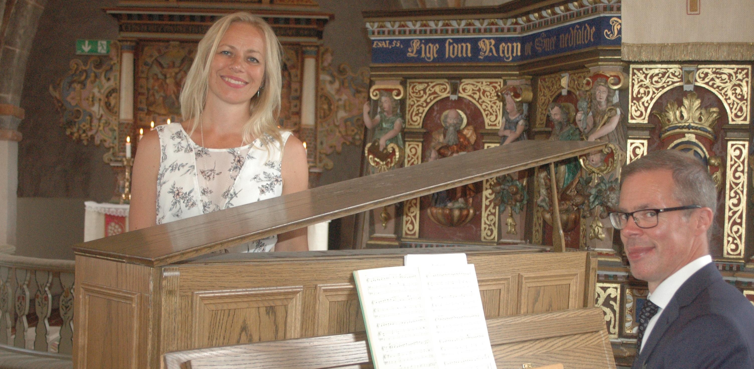 De två musikerna befinner sig vid ett piano och tittar inte i kameran.