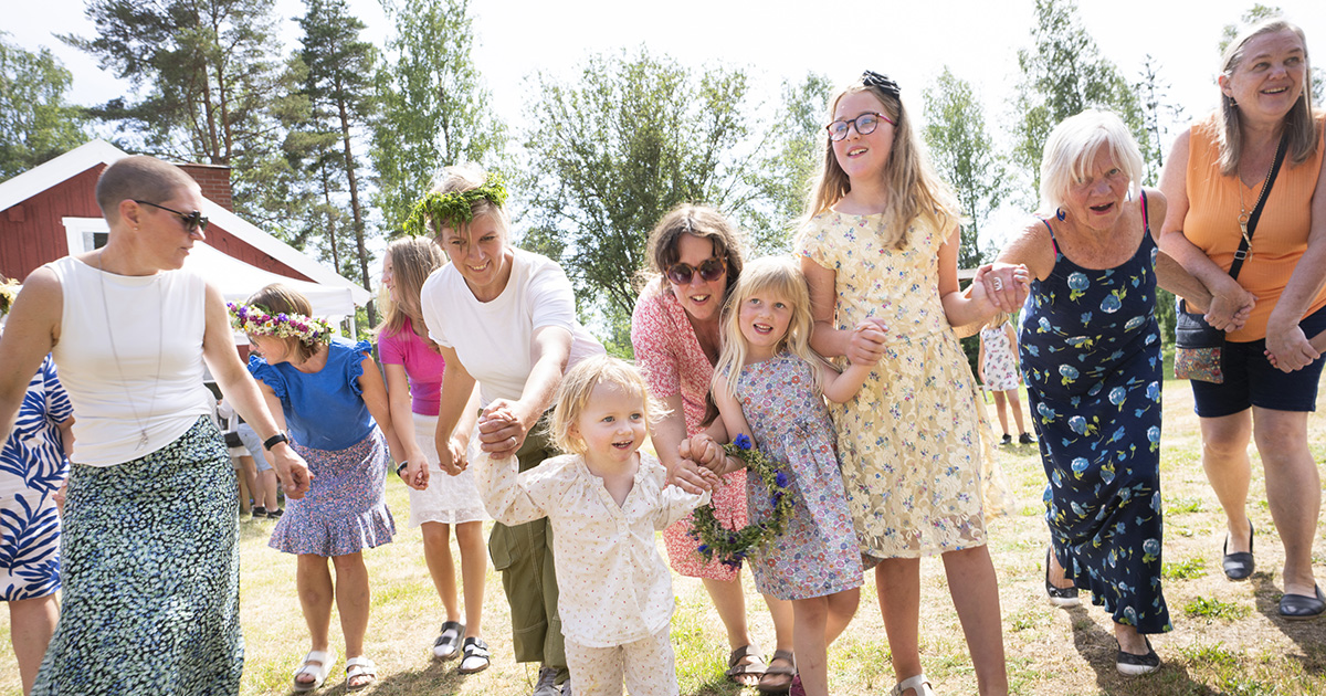 Ett antal vuxna och barn som dansar med blommor i håret.