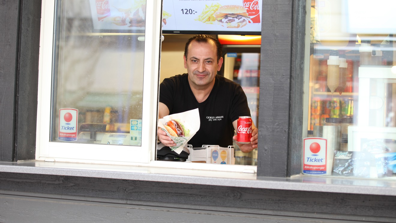 Jakob Swedkarl på Centrumgrillen håller fram en hamburgare och en Coca-Cola.