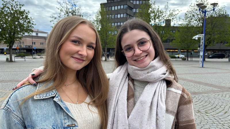 Två unga tjejer står tillsammans på torget i Vetlanda med stadshuset i bakgrunden