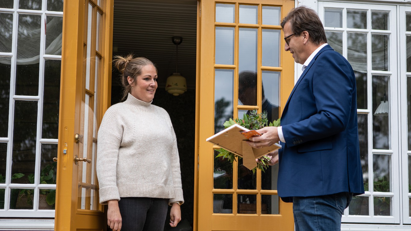 Stewe Jonsson överraskar Judith Engqvist i dörröppningen, med diplom och blommor.