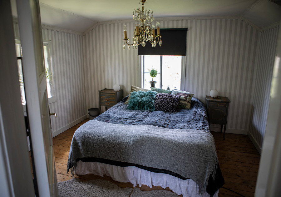 En stor säng i ett sovrum med randiga tapeter.
