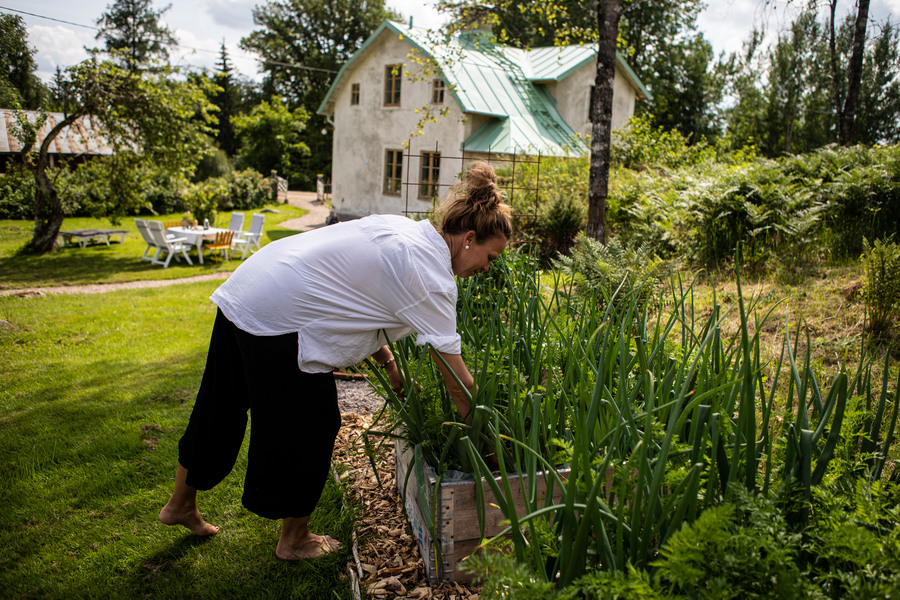 Mariette står lutad över ett trädgårdsland med lökväxter.
