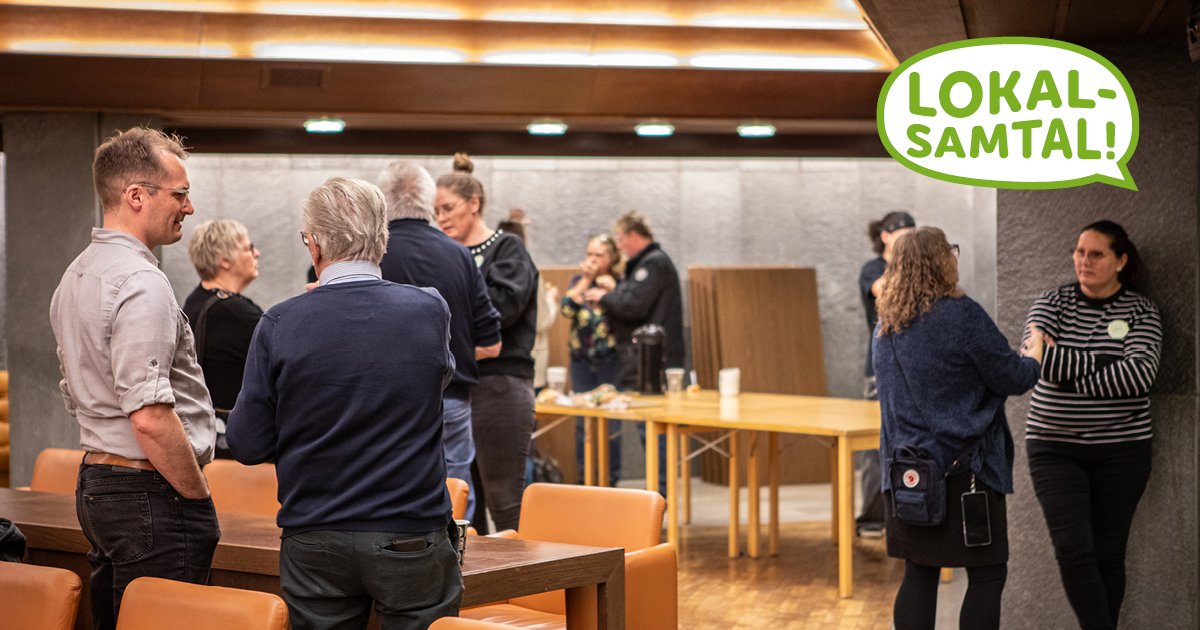 En samling människor ser ut att diskutera olika saker med varandra i en samlingslokal.