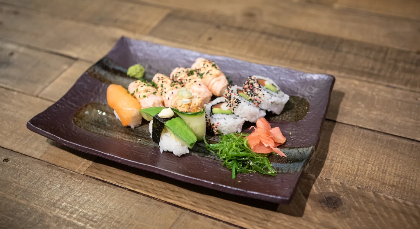En tallrik med sushi på ett träbord.