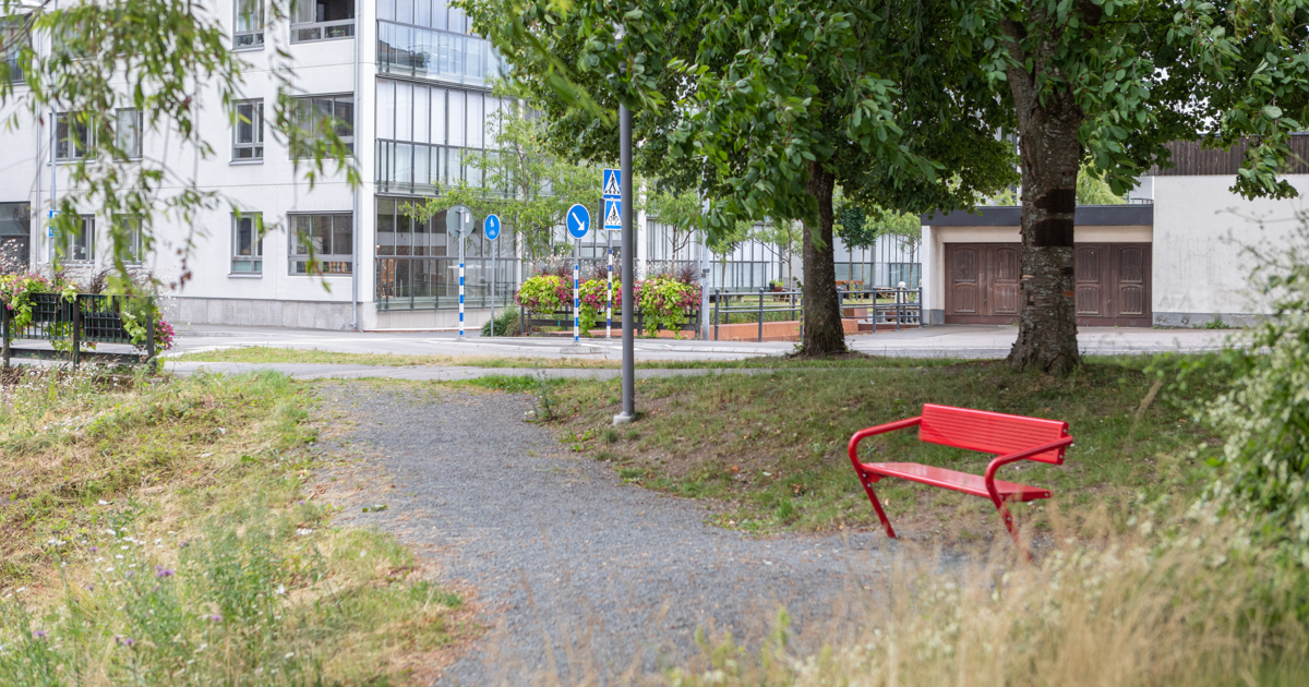 En tom parkmiljö med en röd bänk.