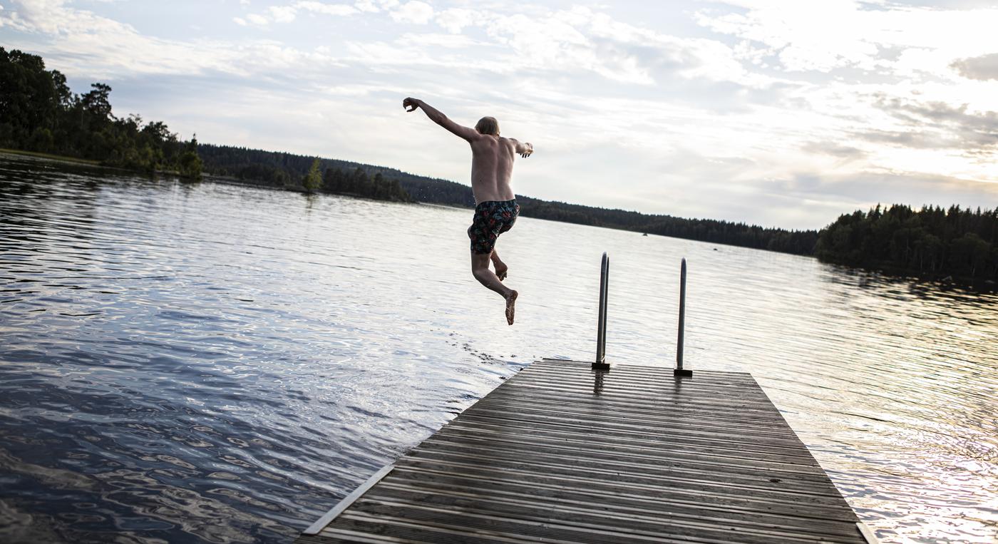 En kille hoppar i vattnet från en brygga