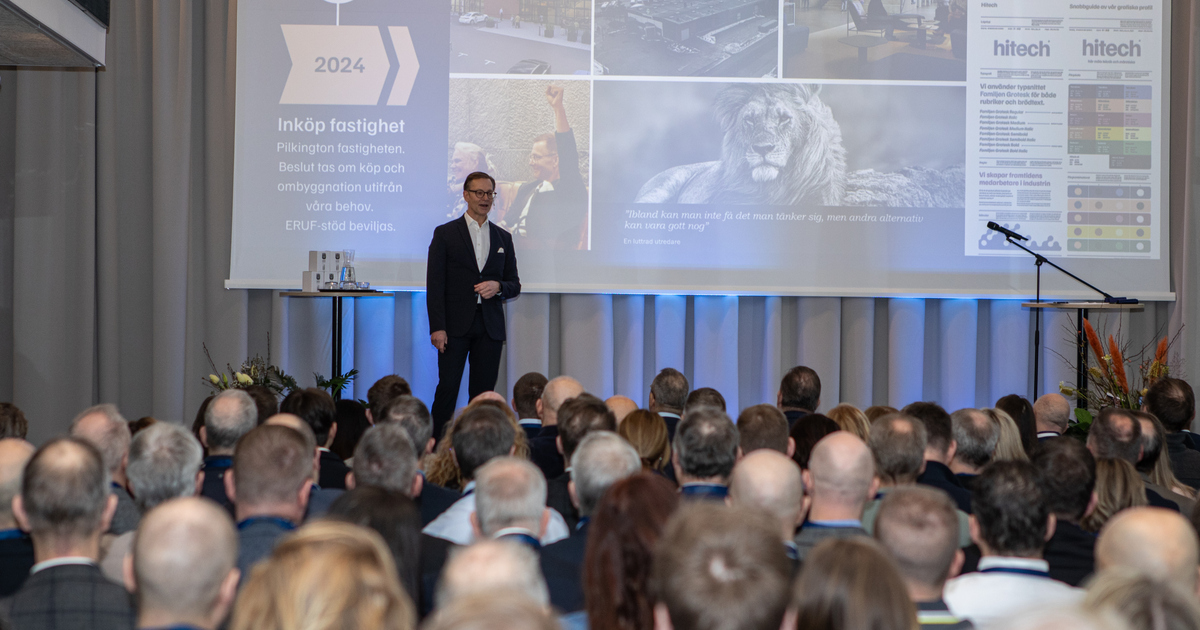 En man står på en scen framför en sittande publik.