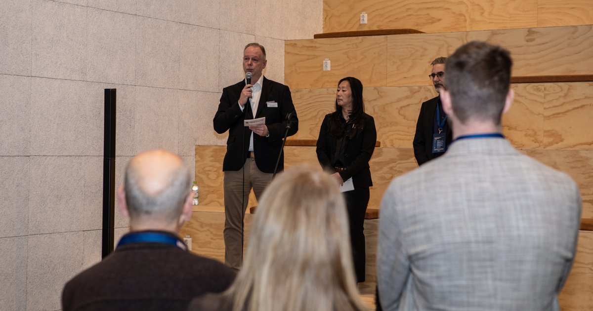 Tre personer presenterar framför en samling åhörare.