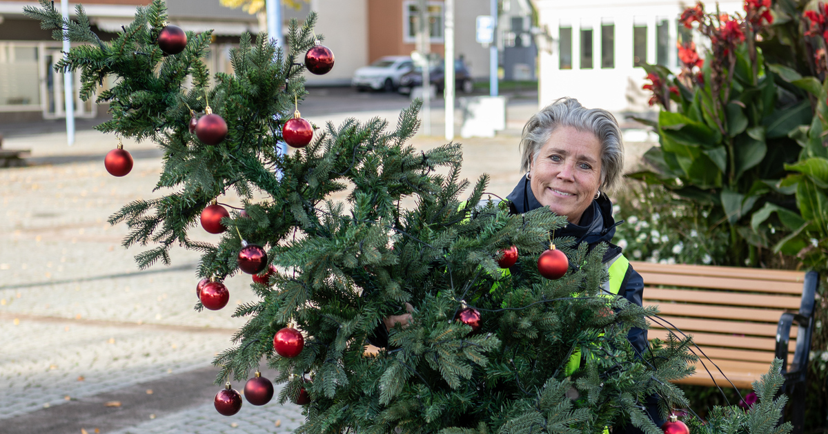 En kvinna håller i en plastgran på ett torg.