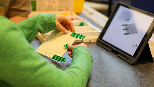 Ett barn bygger med lego och programmerar med en surfplatta.