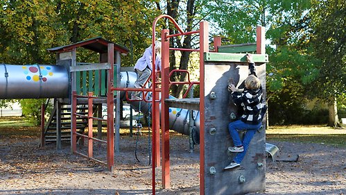 Två barn klättrar i en klätterställning på en lekplats.