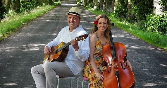 Duo Danica och Magnus Jansson sitter på en väg med sina instrument.